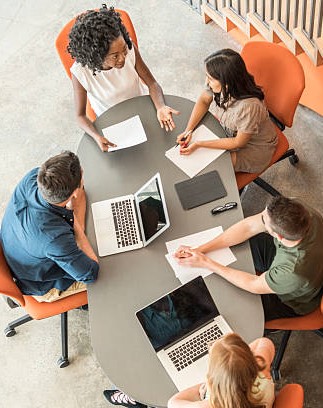 Candid portrait of business colleagues in meeting with laptops and making notes